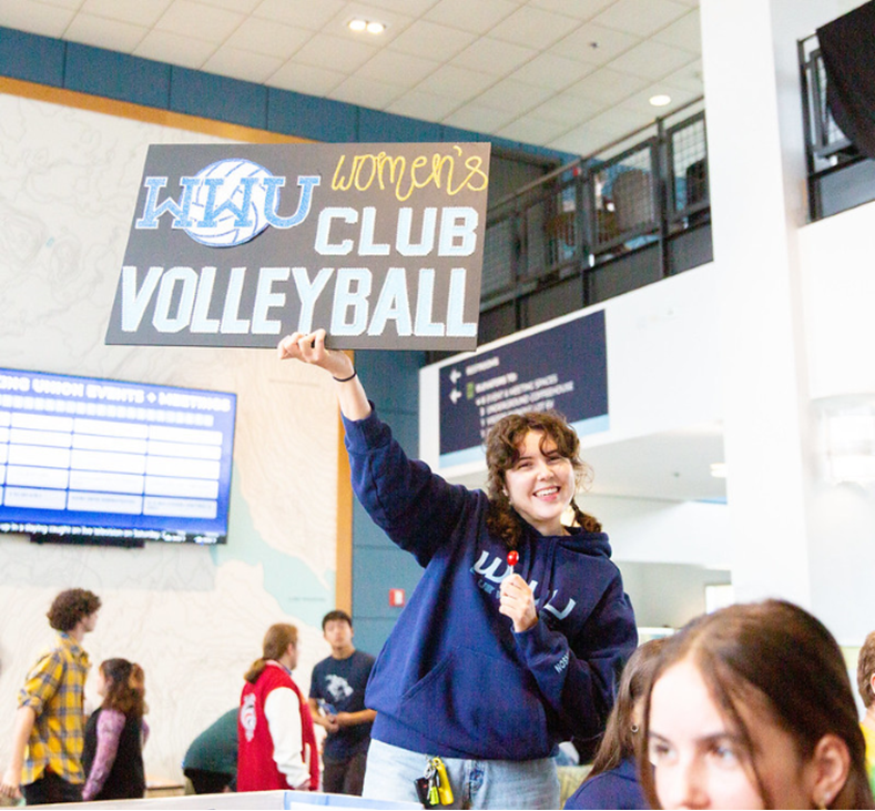Woman holding a sign promoting WWU Club Volleyball